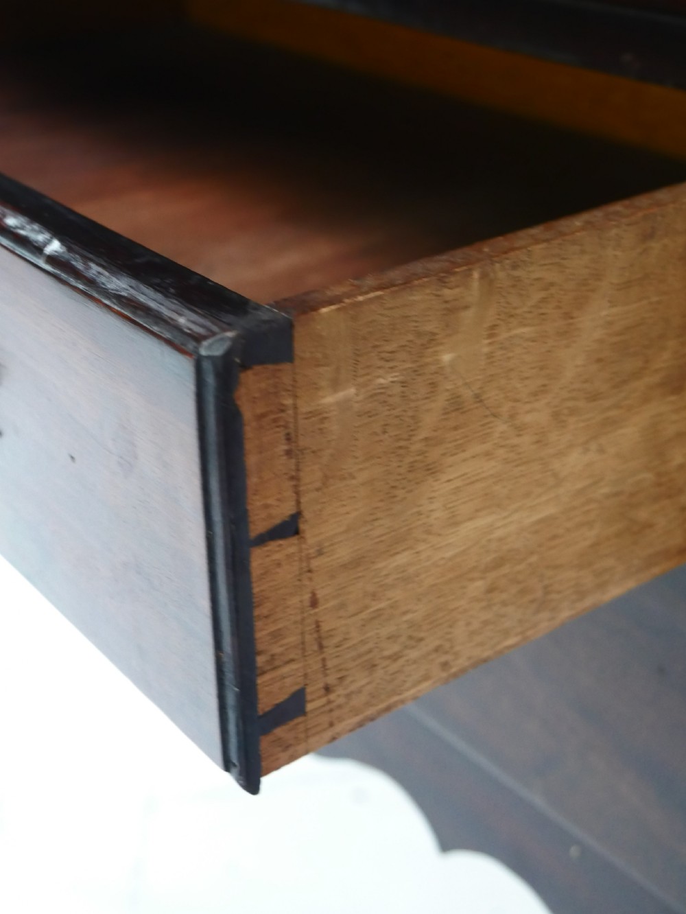 A dark brown Georgian mahogany lowboy featuring three drawers with brass handles and a shaped lower apron on square legs. View VIII