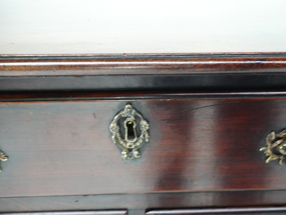 A dark brown Georgian mahogany lowboy featuring three drawers with brass handles and a shaped lower apron on square legs. View IX