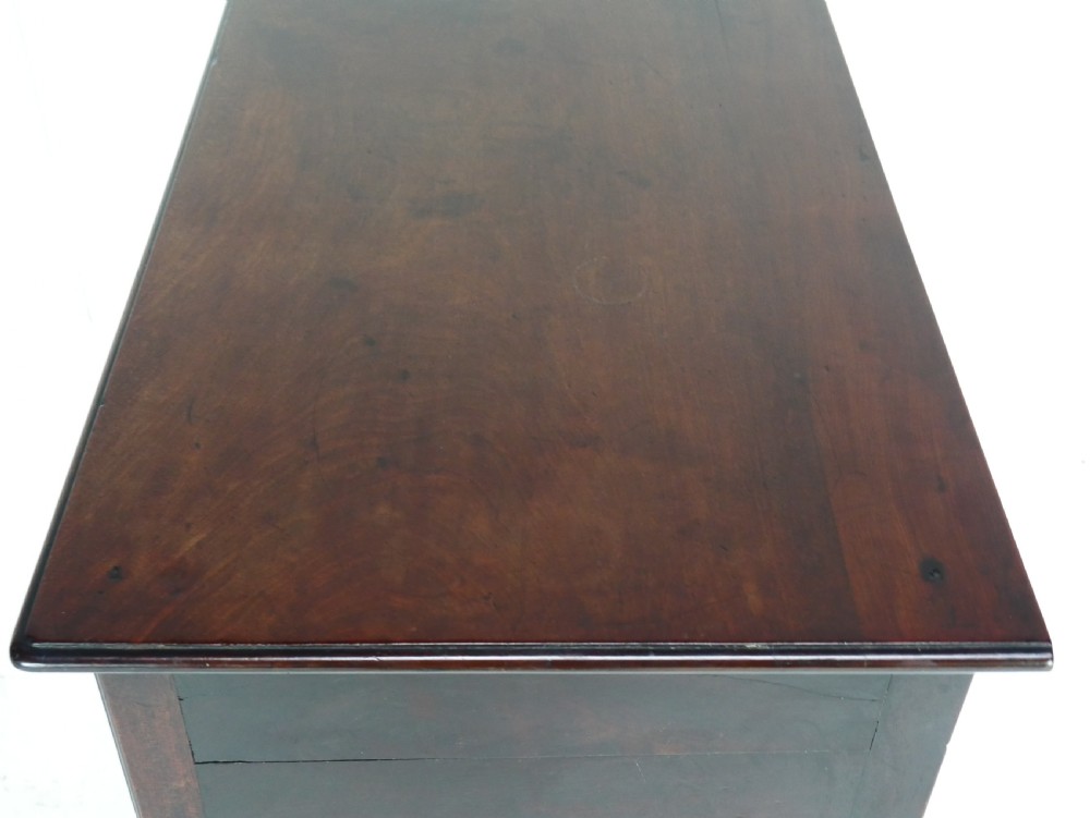 A dark brown Georgian mahogany lowboy featuring three drawers with brass handles and a shaped lower apron on square legs. View XIII