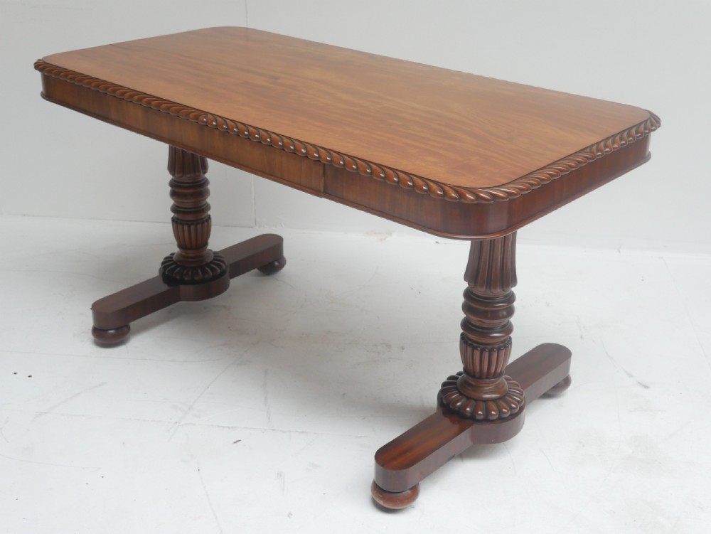 A Regency mahogany sofa writing table featuring a carved gadrooned edge, twin turned pedestal supports, and plinth feet. View II