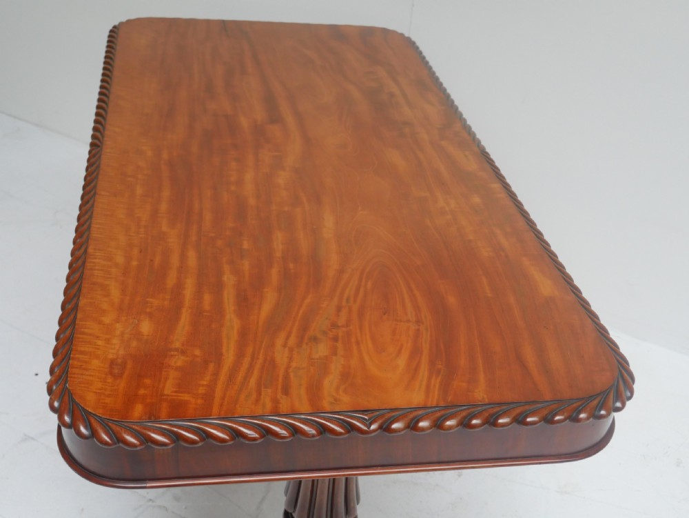 A Regency mahogany sofa writing table featuring a carved gadrooned edge, twin turned pedestal supports, and plinth feet. View V