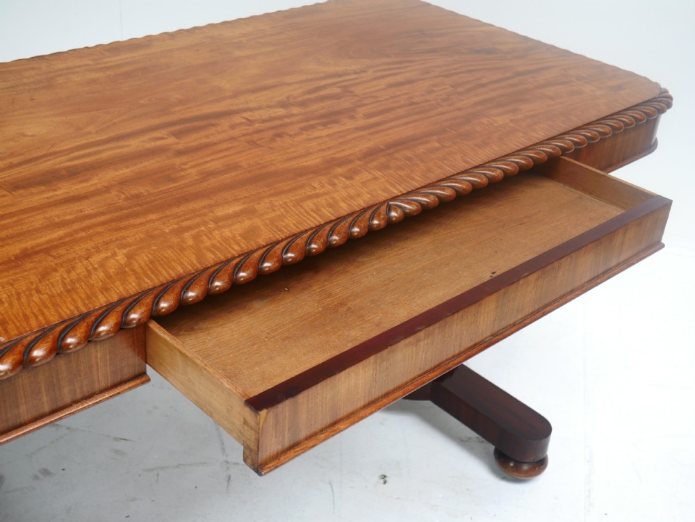 A Regency mahogany sofa writing table featuring a carved gadrooned edge, twin turned pedestal supports, and plinth feet. View VI