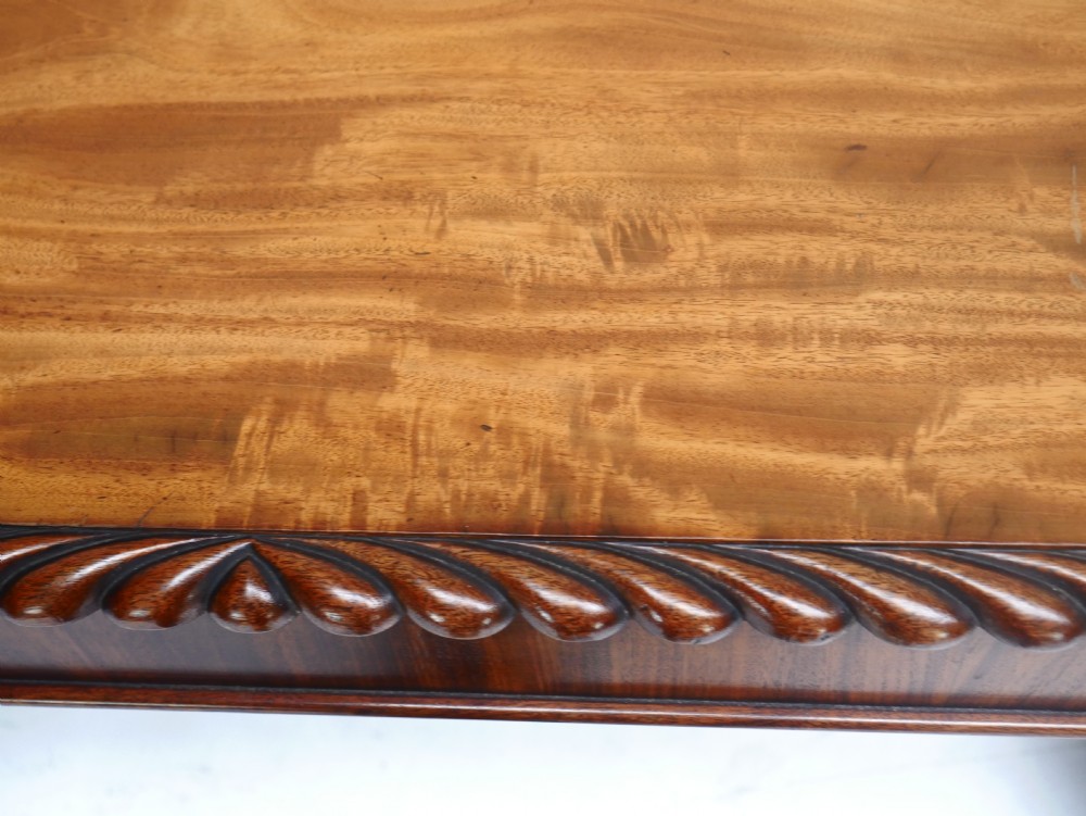 A Regency mahogany sofa writing table featuring a carved gadrooned edge, twin turned pedestal supports, and plinth feet. View X
