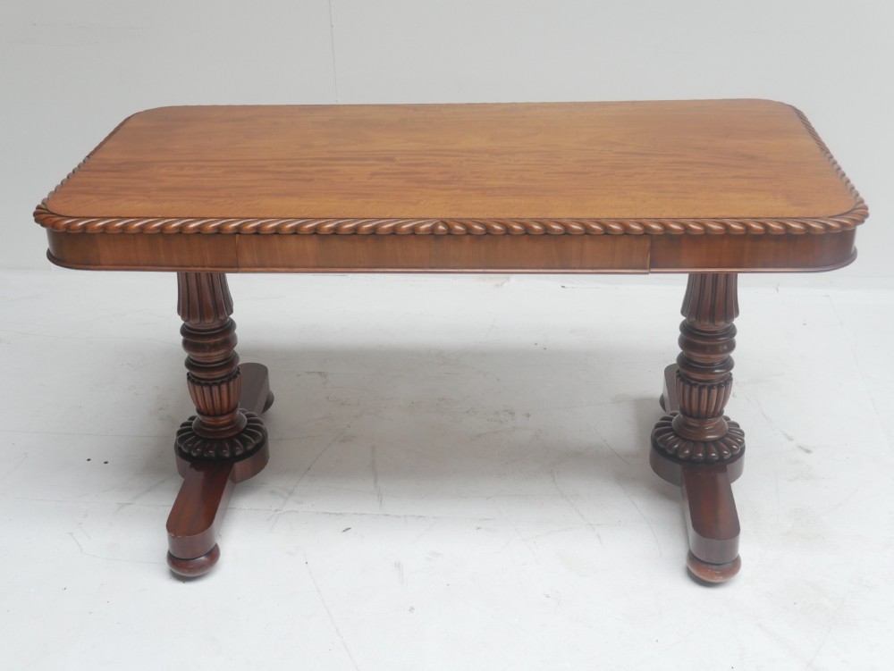 A Regency mahogany sofa writing table featuring a carved gadrooned edge, twin turned pedestal supports, and plinth feet. View XI