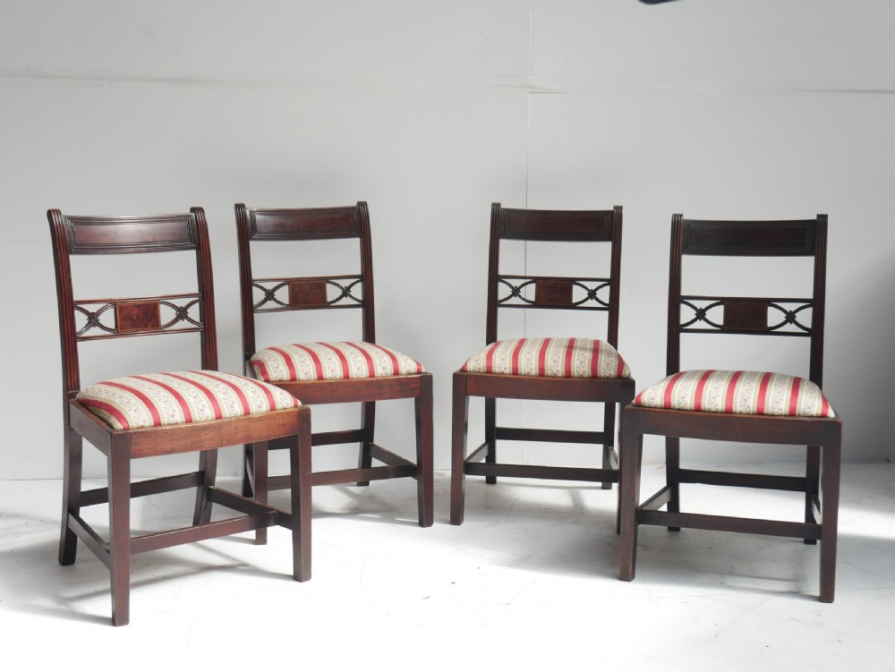 Set of four dark mahogany Regency dining chairs with reeded frames and red and cream striped fabric seats.