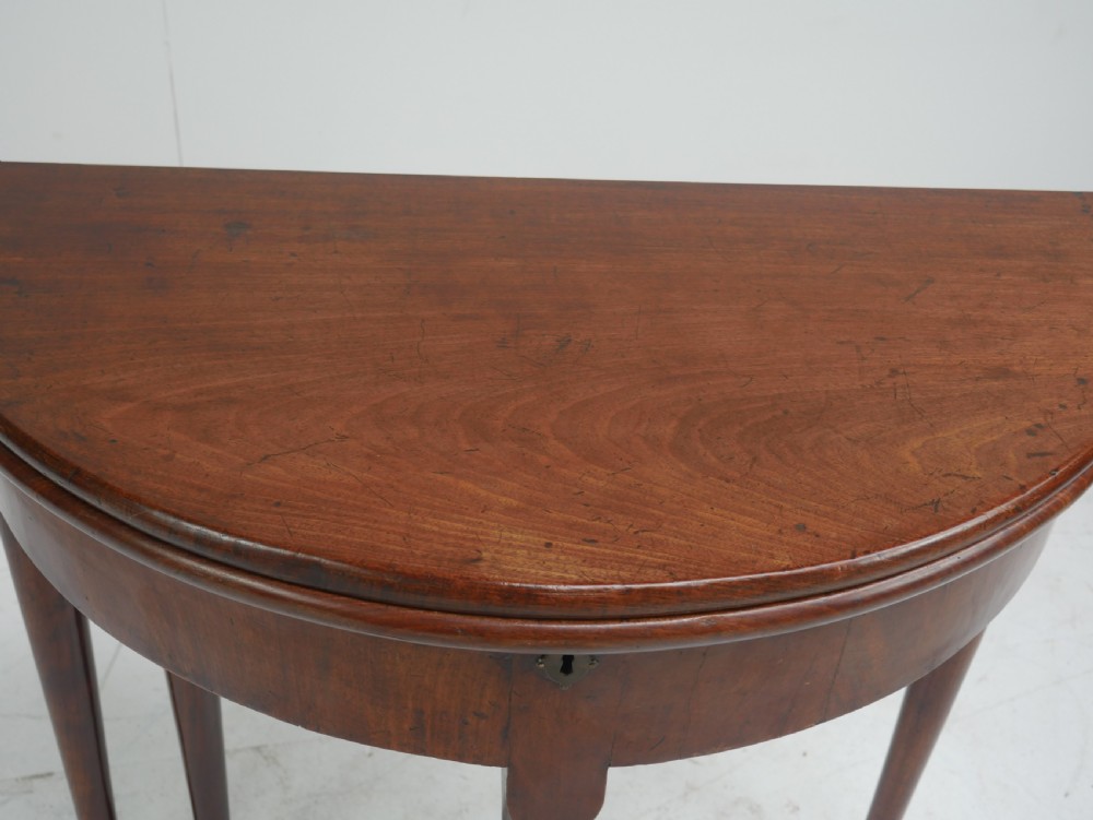 An 18th-century mahogany demi-lune games table featuring a folding semi-circular top supported by slender legs with pad feet. View VII