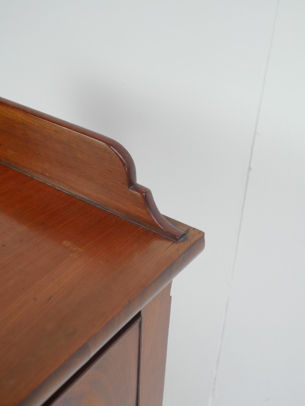 A Regency flame mahogany sideboard featuring five drawers with brass lion mask handles, turned reeded legs, and carved corner brackets. View IX