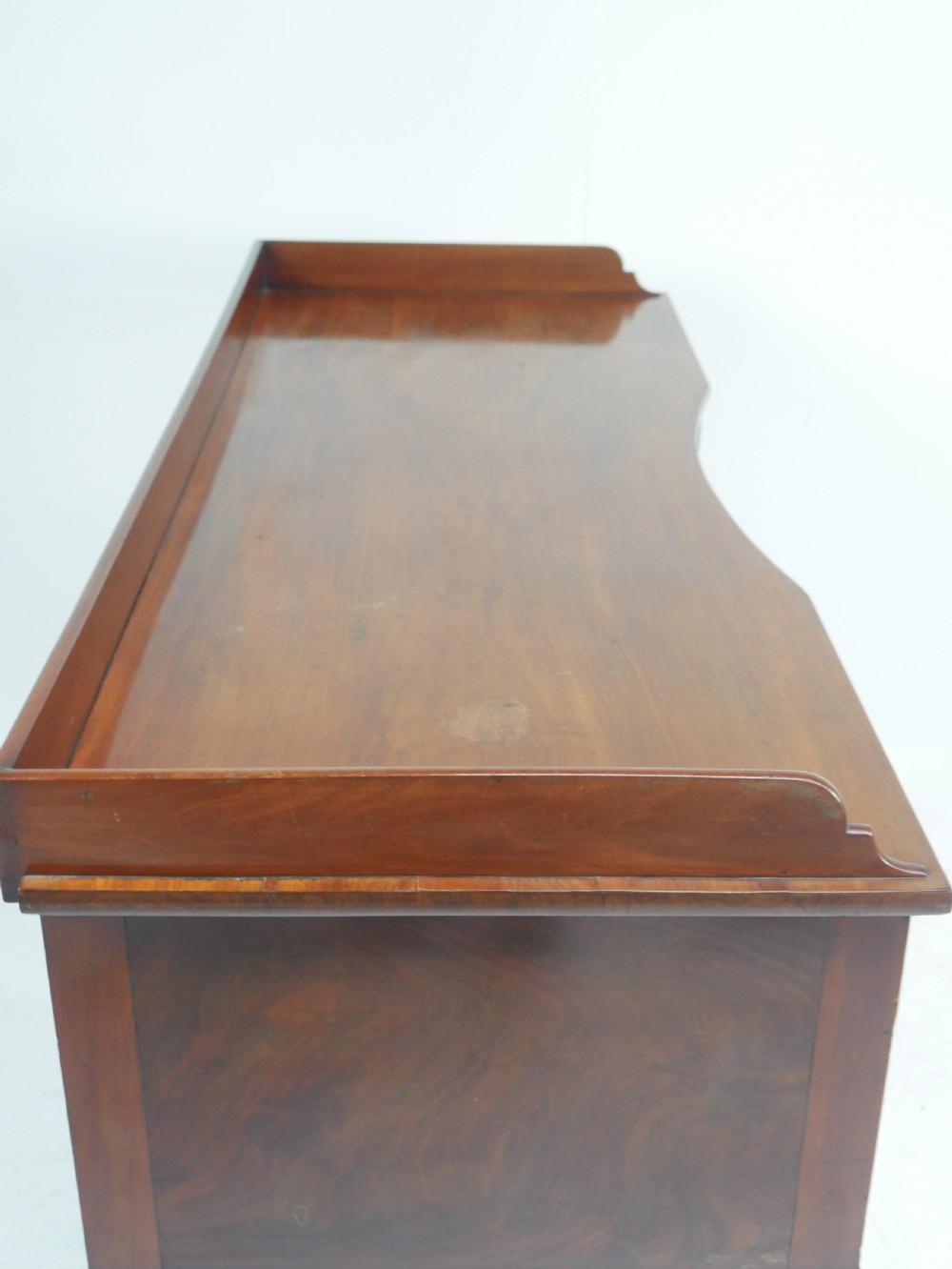 A Regency flame mahogany sideboard featuring five drawers with brass lion mask handles, turned reeded legs, and carved corner brackets. View X