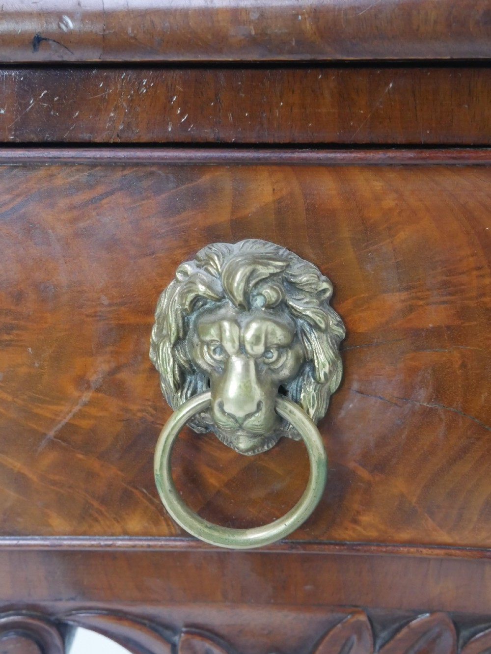 A Regency flame mahogany sideboard featuring five drawers with brass lion mask handles, turned reeded legs, and carved corner brackets. View XIV