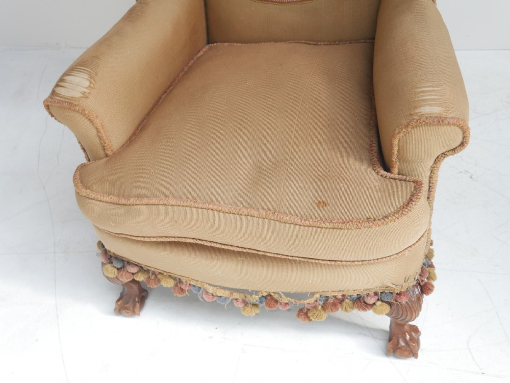 A pair of 1920s wingback armchairs upholstered in gold fabric featuring oval embroidered back panels and carved walnut ball and claw feet. View X