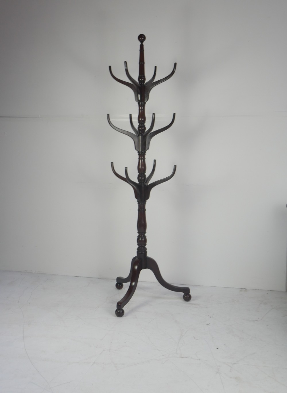 A tall 19th-century turned dark mahogany hat and coat stand with tiered curved branches and a tripod base. View X