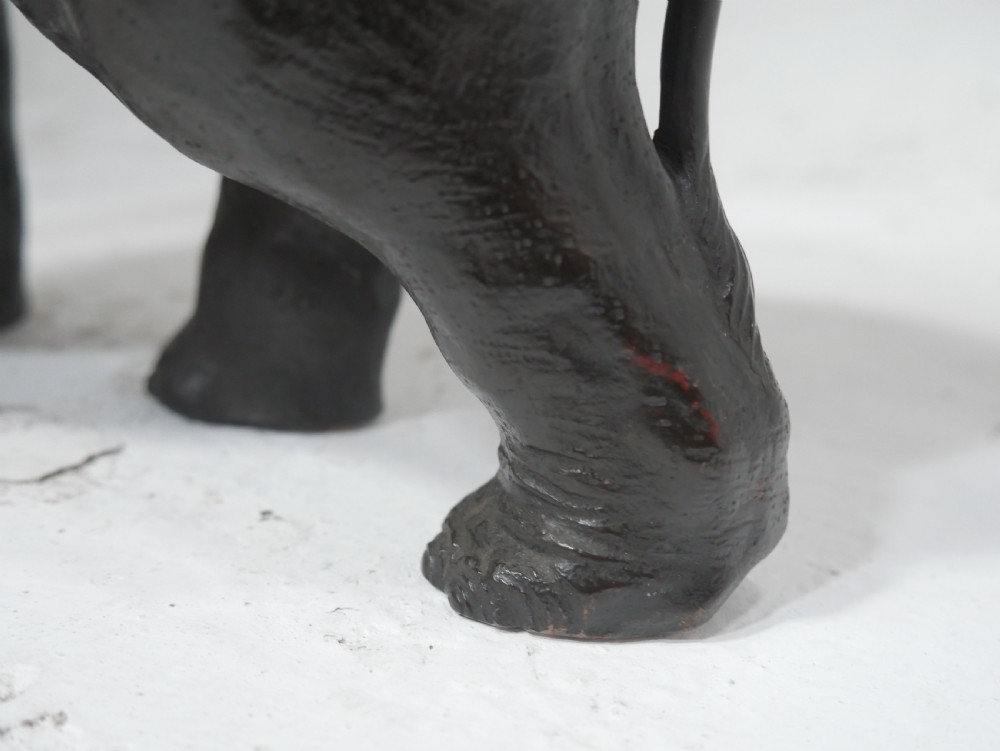 A dark patinated bronze figure of an elephant in mid-stride featuring light-coloured tusks and textured skin detail. View XIII