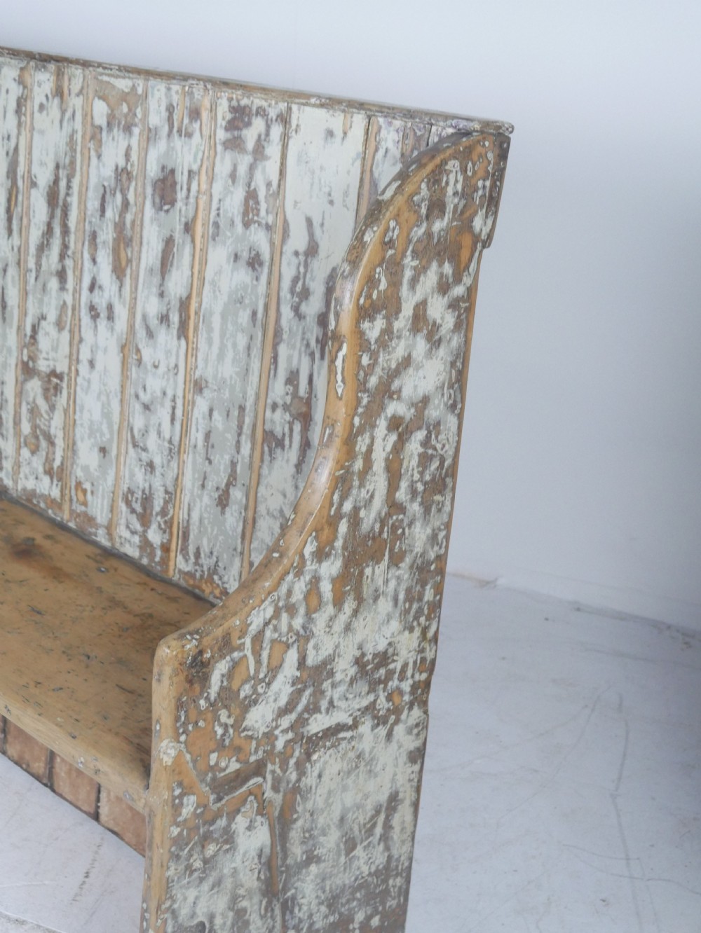A large high-backed wooden settle bench featuring distressed cream paint over natural wood and vertical panelled detailing. View V