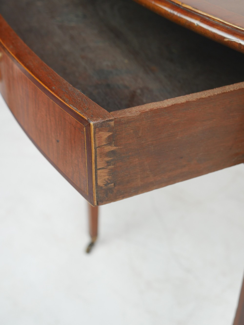 A Georgian mahogany Pembroke table featuring two drop leaves, a single drawer with a brass handle, string inlay on square tapered legs, and brass castors. View X