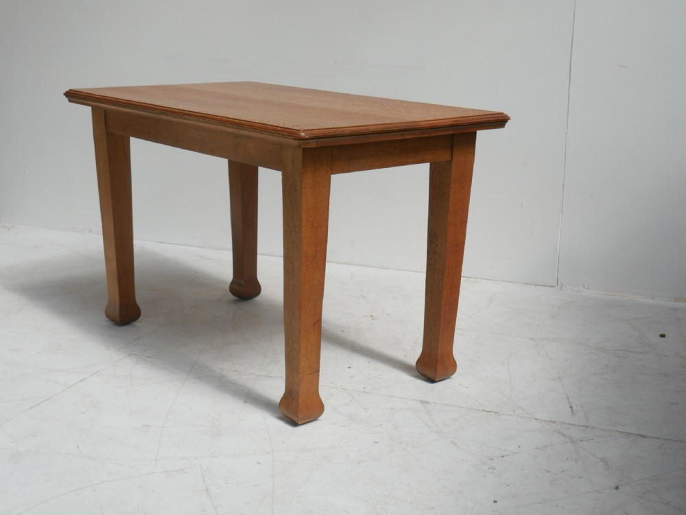 A rectangular solid oak table from the 1920s featuring tapered legs with flared feet and a moulded top edge.