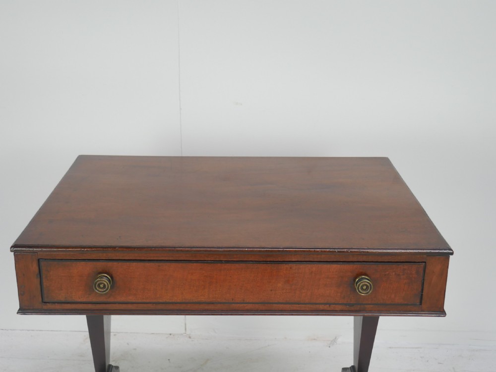 A Regency mahogany side table featuring a single drawer with brass knobs, a turned cross stretcher, and splayed legs on castors. View II