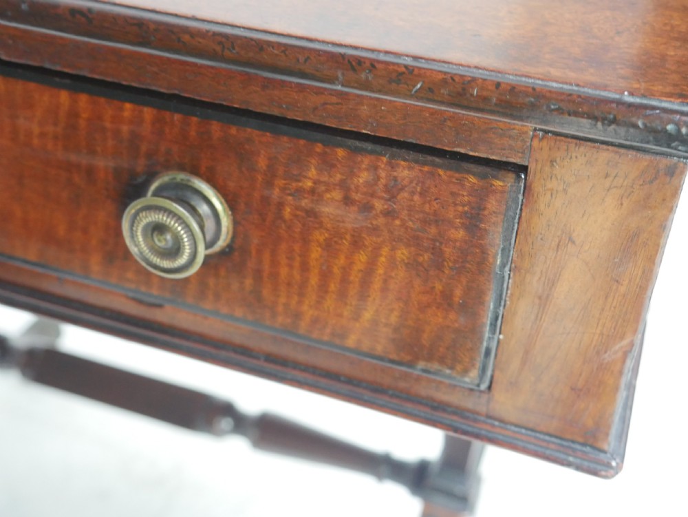 A Regency mahogany side table featuring a single drawer with brass knobs, a turned cross stretcher, and splayed legs on castors. View V