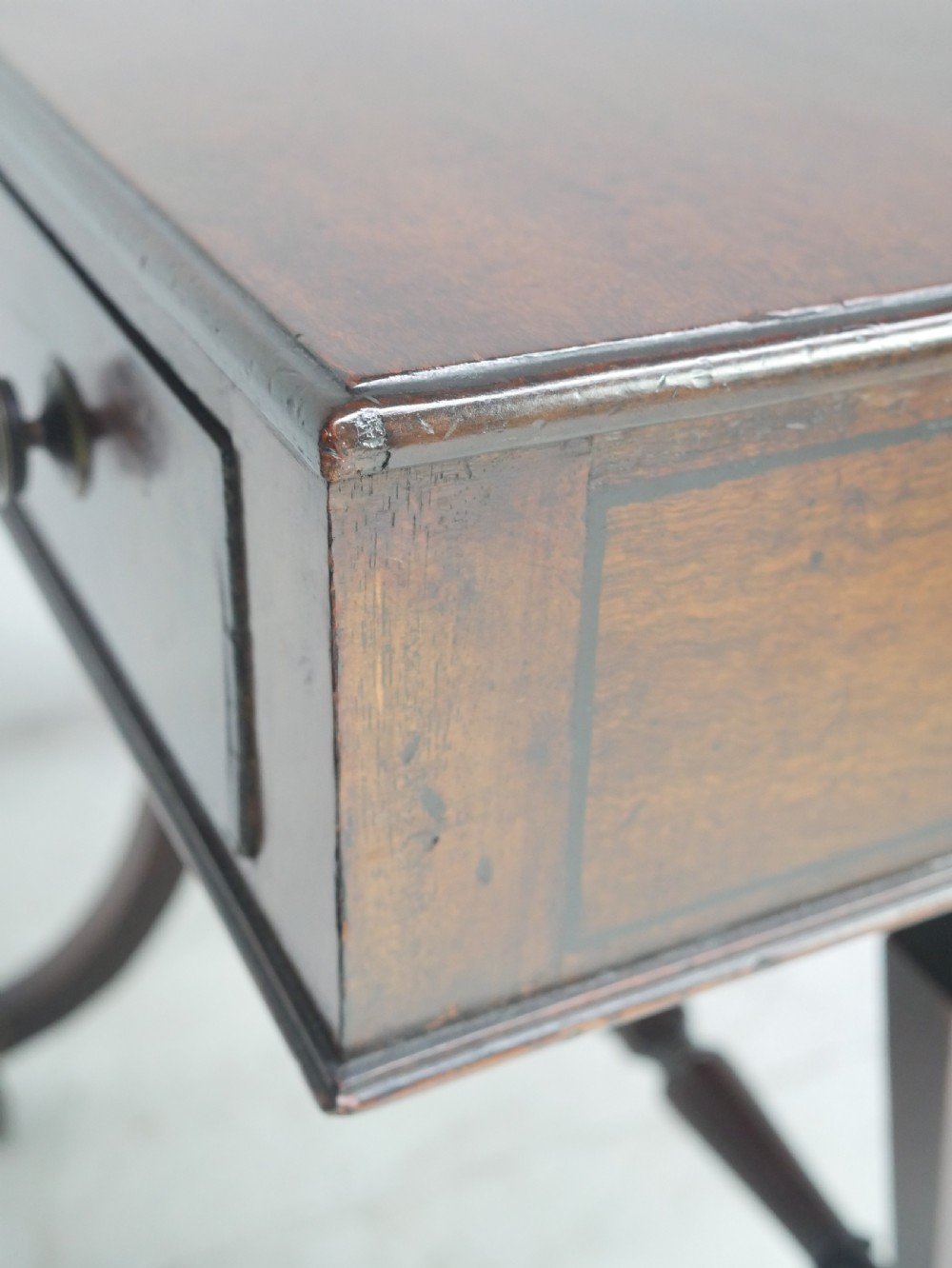 A Regency mahogany side table featuring a single drawer with brass knobs, a turned cross stretcher, and splayed legs on castors. View VII