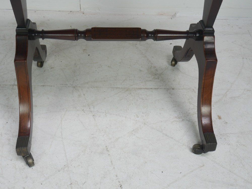A Regency mahogany side table featuring a single drawer with brass knobs, a turned cross stretcher, and splayed legs on castors. View X