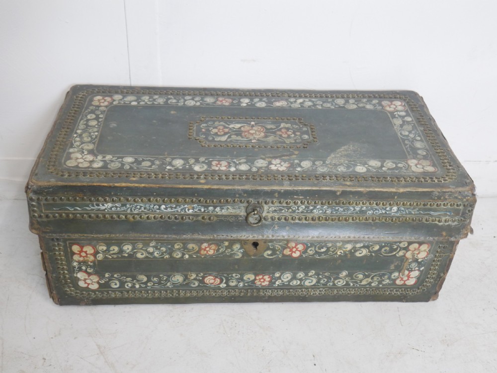 A dark green rectangular leather trunk decorated with hand-painted floral borders and studded brass tacks around the edges.