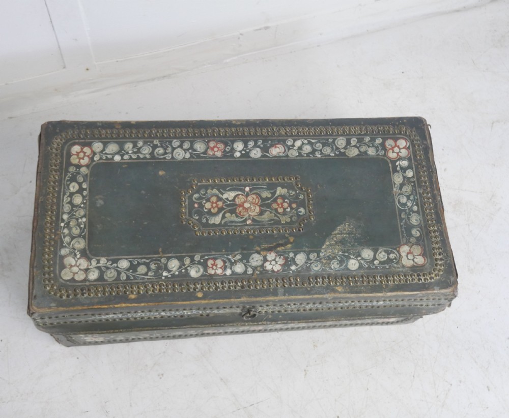 A dark green rectangular leather trunk decorated with hand-painted floral borders and studded brass tacks around the edges. View V