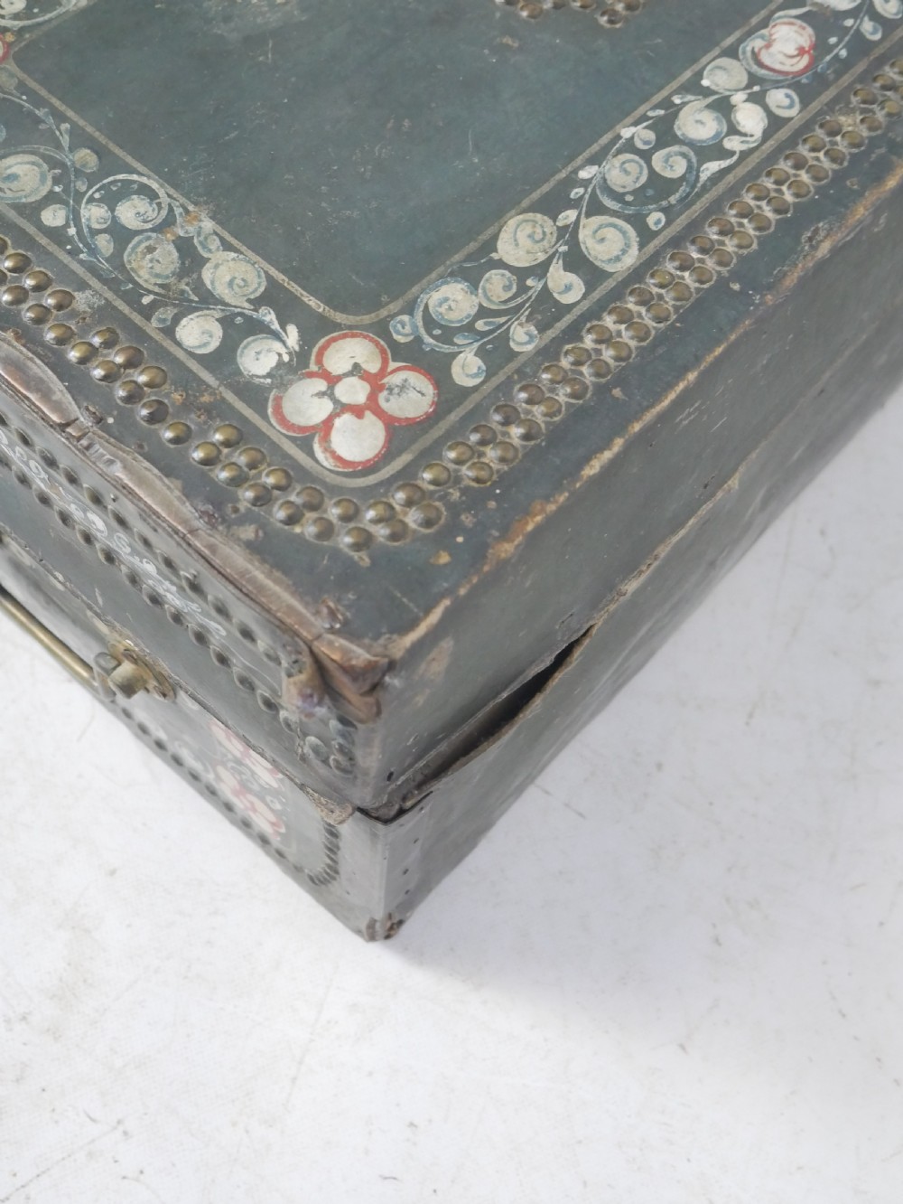 A dark green rectangular leather trunk decorated with hand-painted floral borders and studded brass tacks around the edges. View XIII