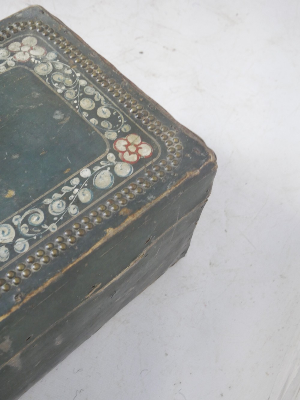 A dark green rectangular leather trunk decorated with hand-painted floral borders and studded brass tacks around the edges. View XIV