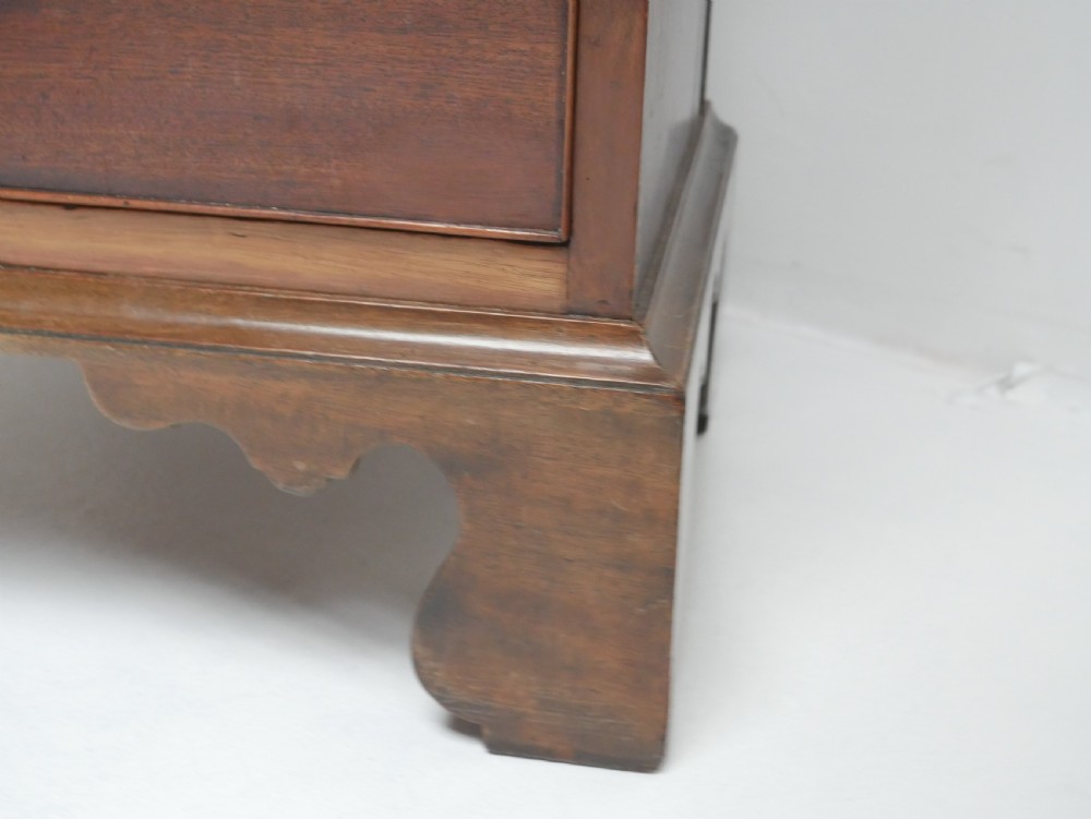 A tall, narrow mahogany chest of drawers featuring seven graduated drawers with brass drop handles and decorative shaped bracket feet. View VIII