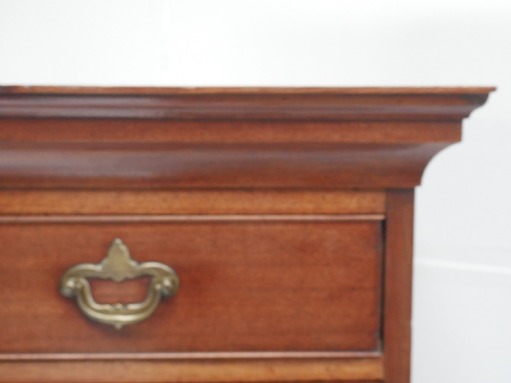 A tall, narrow mahogany chest of drawers featuring seven graduated drawers with brass drop handles and decorative shaped bracket feet. View X