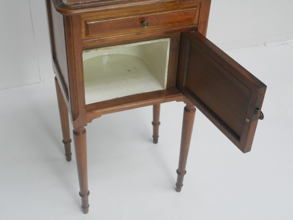 A French provincial walnut bedside cabinet with a red marble top, single drawer, inlaid wooden door, and slender turned legs. View VI