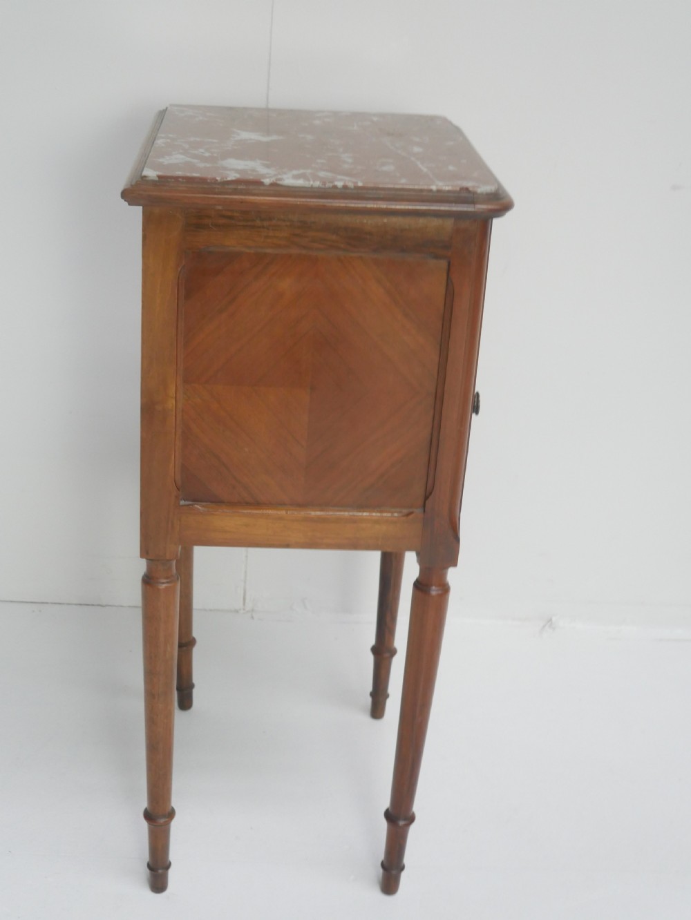 A French provincial walnut bedside cabinet with a red marble top, single drawer, inlaid wooden door, and slender turned legs. View VIII
