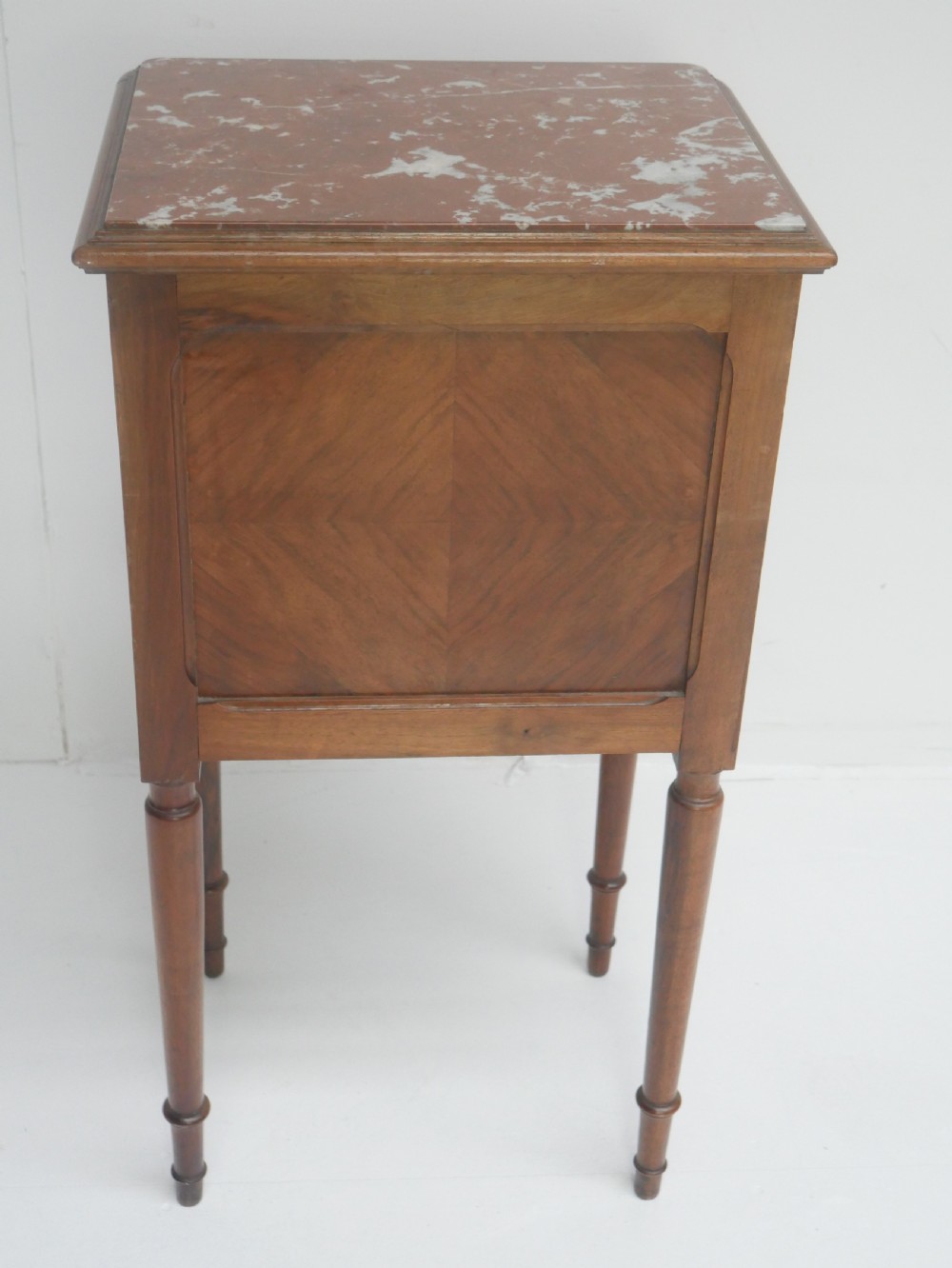 A French provincial walnut bedside cabinet with a red marble top, single drawer, inlaid wooden door, and slender turned legs. View XI