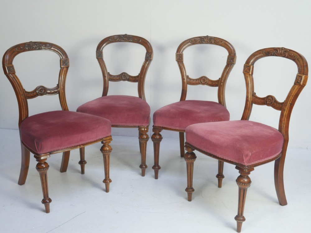 A set of four 19th-century Victorian walnut balloon-back chairs upholstered in rose pink velvet with carved back rails and turned front legs.