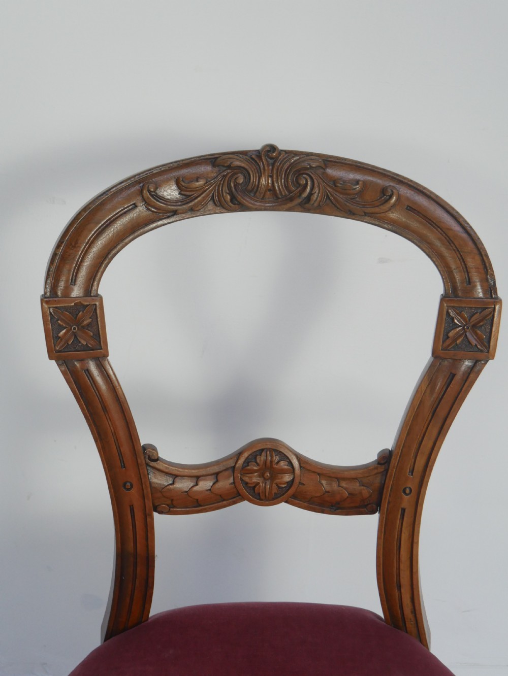 A set of four 19th-century Victorian walnut balloon-back chairs upholstered in rose pink velvet with carved back rails and turned front legs. View II