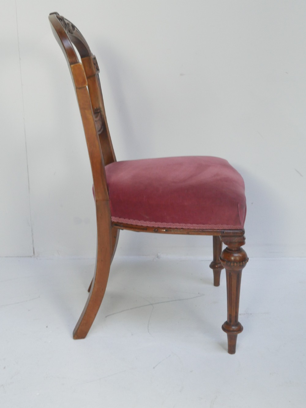 A set of four 19th-century Victorian walnut balloon-back chairs upholstered in rose pink velvet with carved back rails and turned front legs. View IV