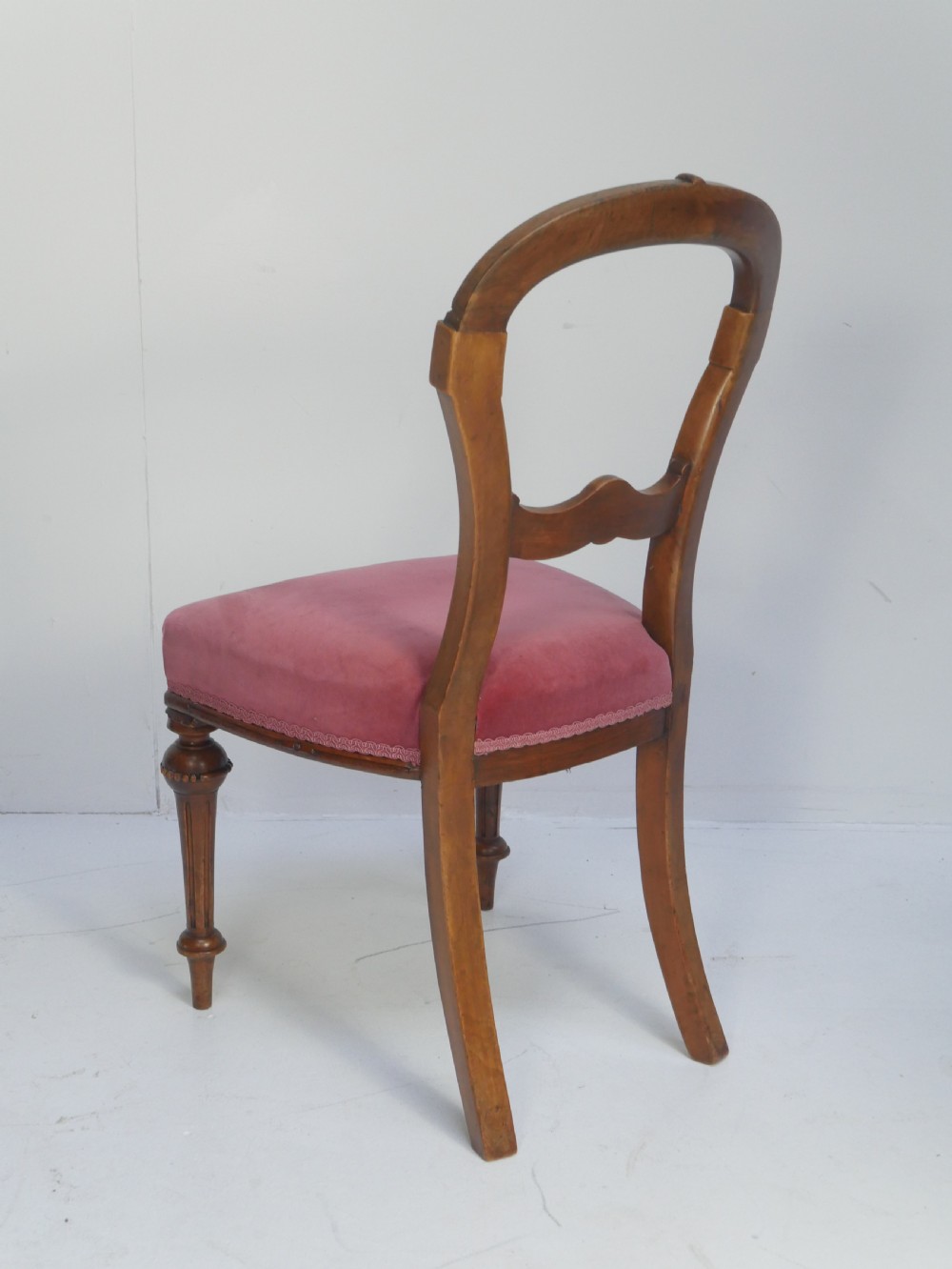 A set of four 19th-century Victorian walnut balloon-back chairs upholstered in rose pink velvet with carved back rails and turned front legs. View V