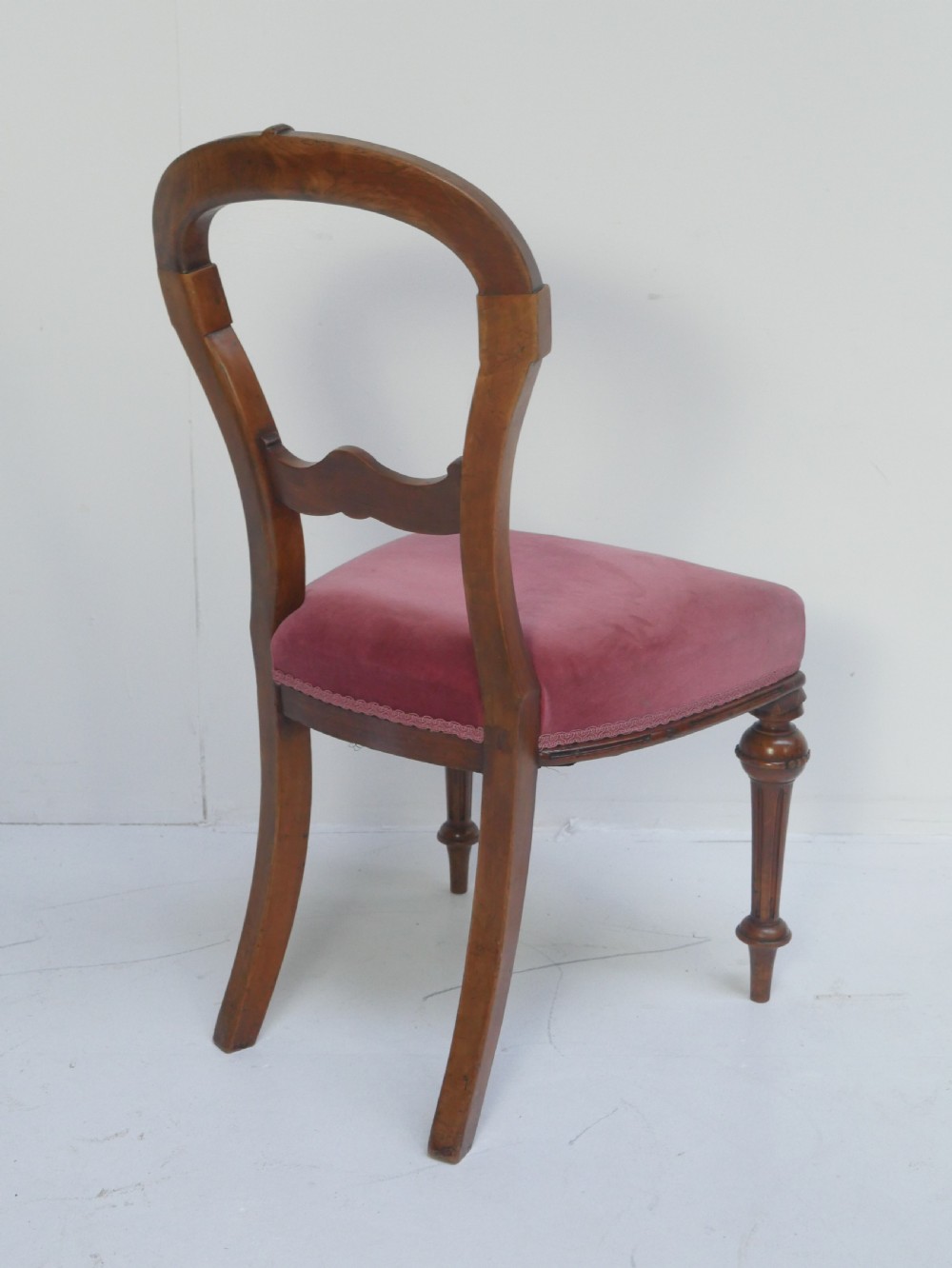 A set of four 19th-century Victorian walnut balloon-back chairs upholstered in rose pink velvet with carved back rails and turned front legs. View IX