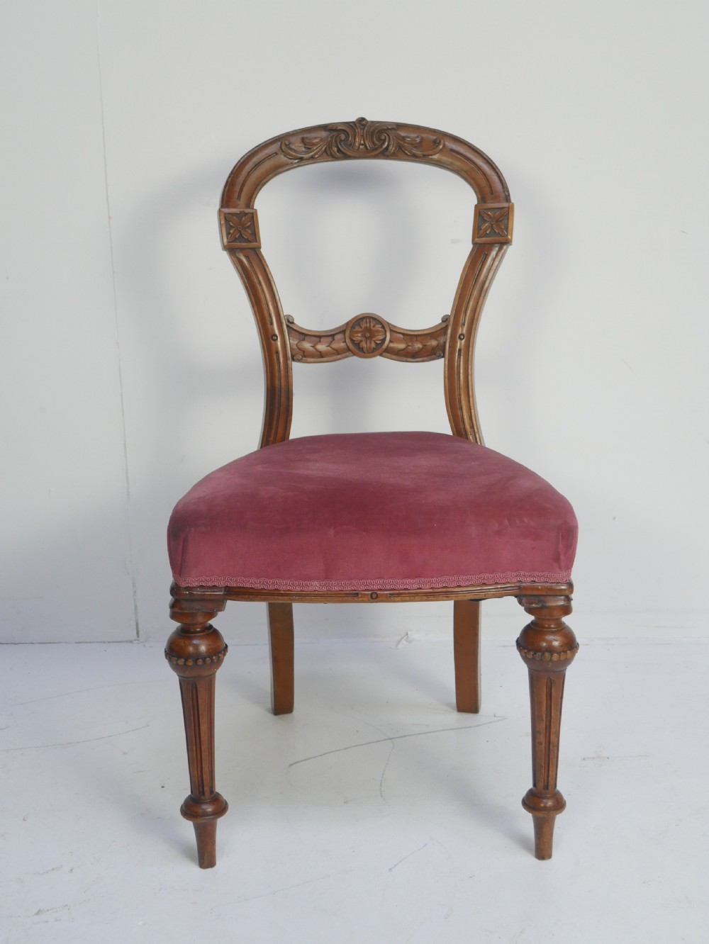 A set of four 19th-century Victorian walnut balloon-back chairs upholstered in rose pink velvet with carved back rails and turned front legs. View X