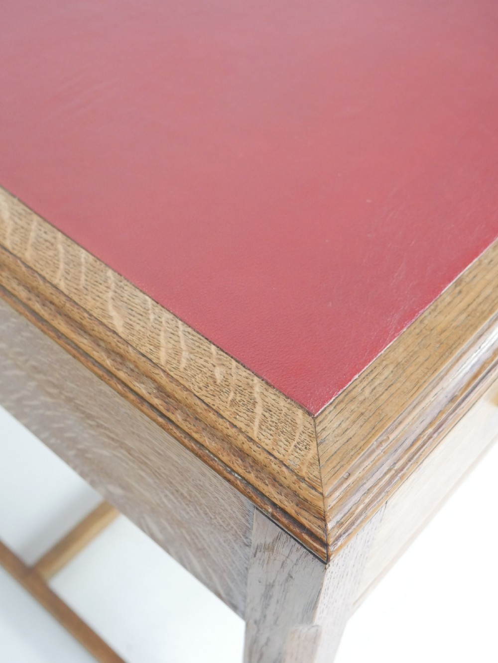 A light oak childs writing desk featuring a red inset leather top, two drawers with wooden pulls, and a square-section frame with a low floor stretcher. View XIV