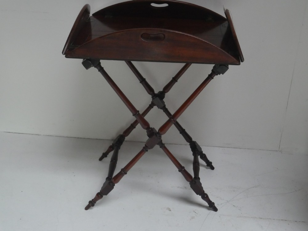 A Regency mahogany butlers tray featuring cutout handles and hinged sides resting on a turned folding X-frame stand. View II