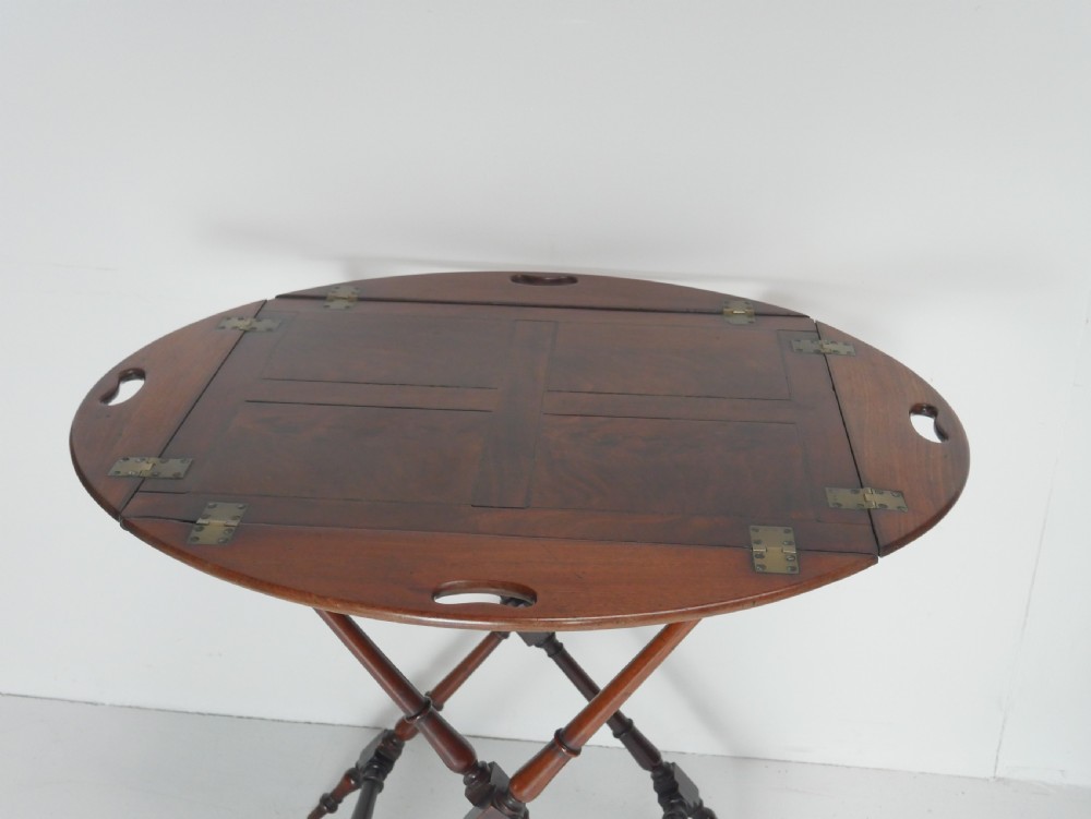 A Regency mahogany butlers tray featuring cutout handles and hinged sides resting on a turned folding X-frame stand. View IV