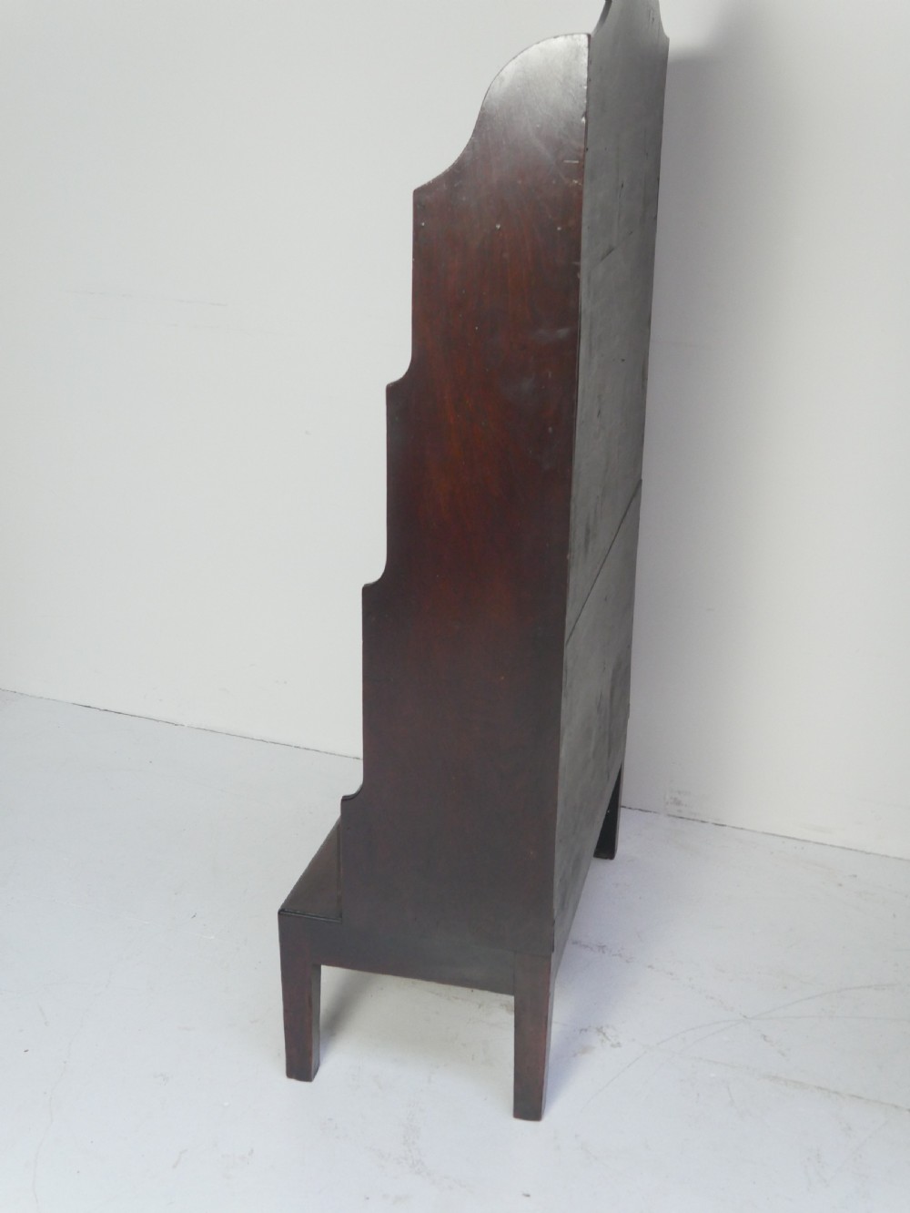 A dark mahogany Georgian waterfall bookcase featuring three open graduated shelves above a single drawer with brass handles. View V