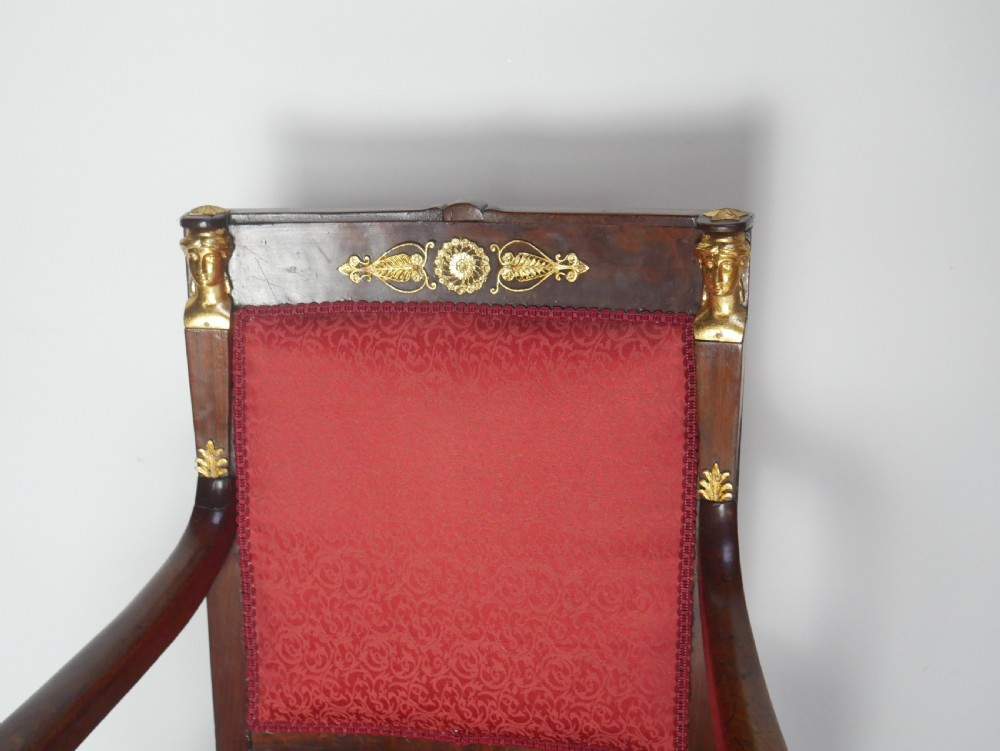 A French Empire style mahogany armchair featuring red damask fabric upholstery, carved armrests, and decorative gilded bronze mounts. View II