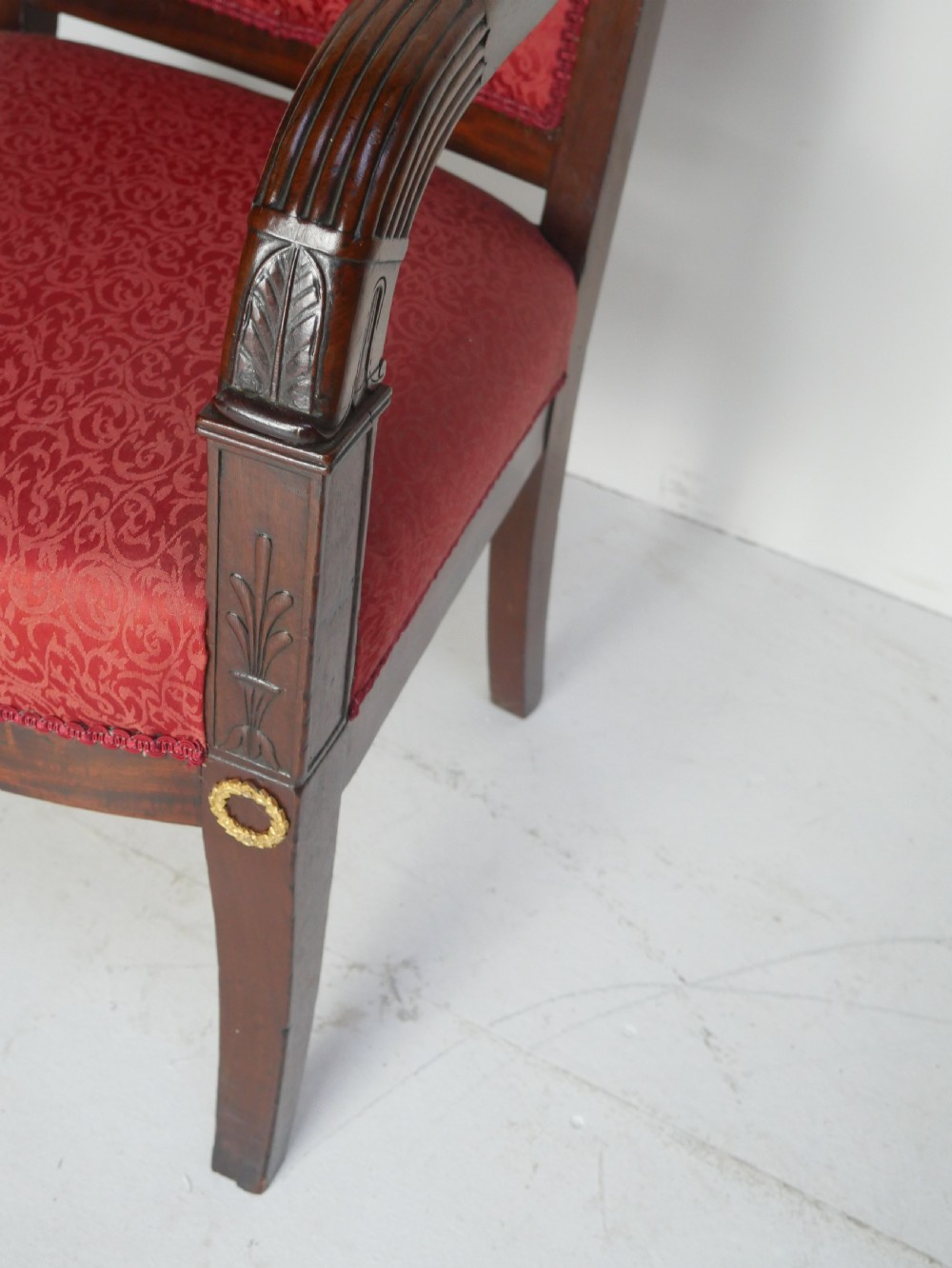 A French Empire style mahogany armchair featuring red damask fabric upholstery, carved armrests, and decorative gilded bronze mounts. View III