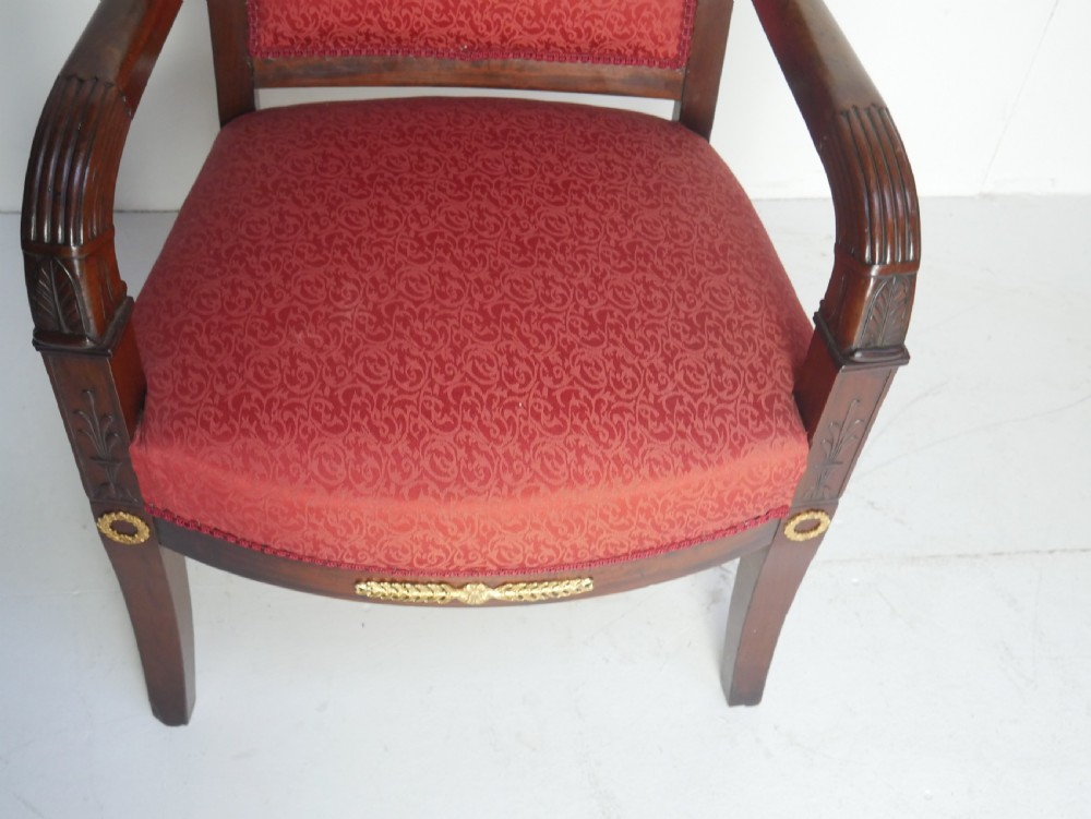 A French Empire style mahogany armchair featuring red damask fabric upholstery, carved armrests, and decorative gilded bronze mounts. View IV