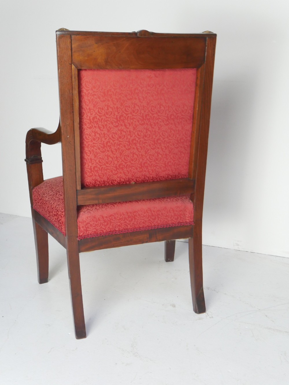 A French Empire style mahogany armchair featuring red damask fabric upholstery, carved armrests, and decorative gilded bronze mounts. View IX