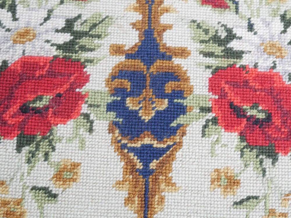 A rectangular antique mahogany piano stool featuring fluted tapered legs, carved central rosettes, and a floral needlepoint tapestry top. View II