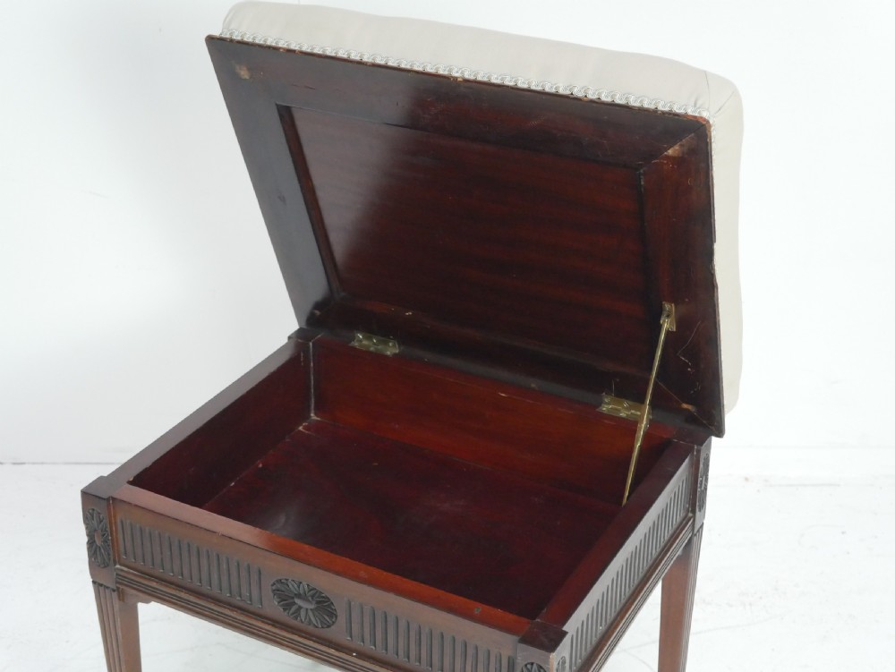 A rectangular antique mahogany piano stool featuring fluted tapered legs, carved central rosettes, and a floral needlepoint tapestry top. View III