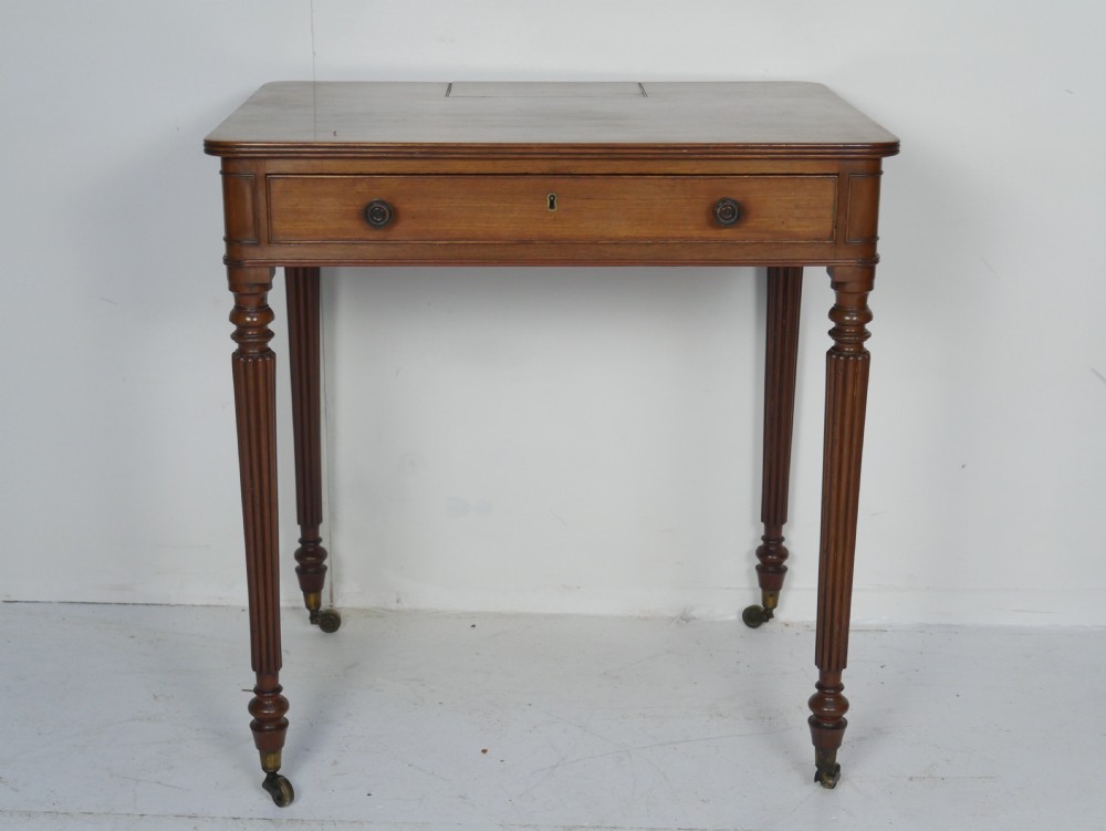 A Regency mahogany chamber writing desk featuring reeded turned legs, a single frieze drawer, and brass castors. View VII