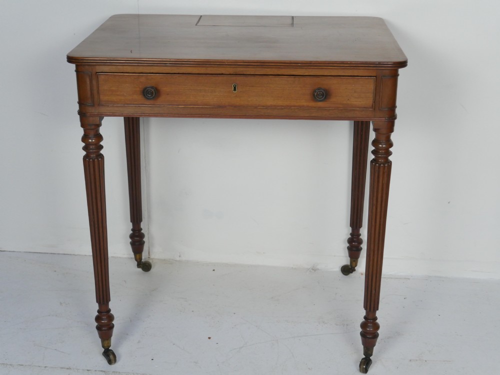 A Regency mahogany chamber writing desk featuring reeded turned legs, a single frieze drawer, and brass castors. View VIII